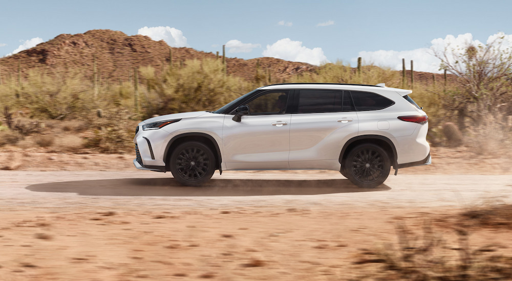 Side view of a white 2024 Toyota Highlander XSE driving through the desert.