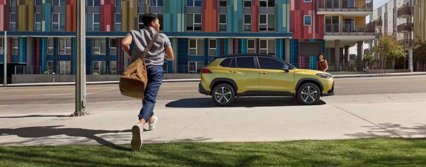 A person is shown running toward a yellow 2023 Toyota Corolla Cross Hybrid XSE.