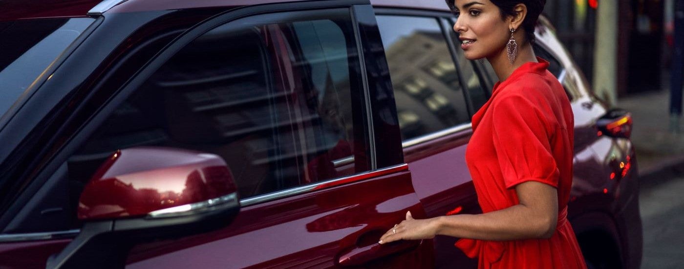 A person is shown opening the door to a red 2024 Toyota Highlander Hybrid Platinum.
